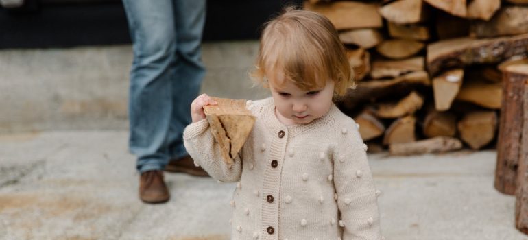 A photograph of a child carrying a small piece of firewood