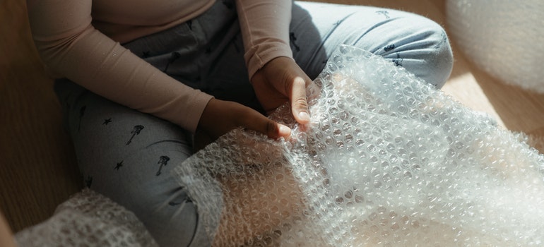 Person in gray long sleeve shirt holding bubble wrap